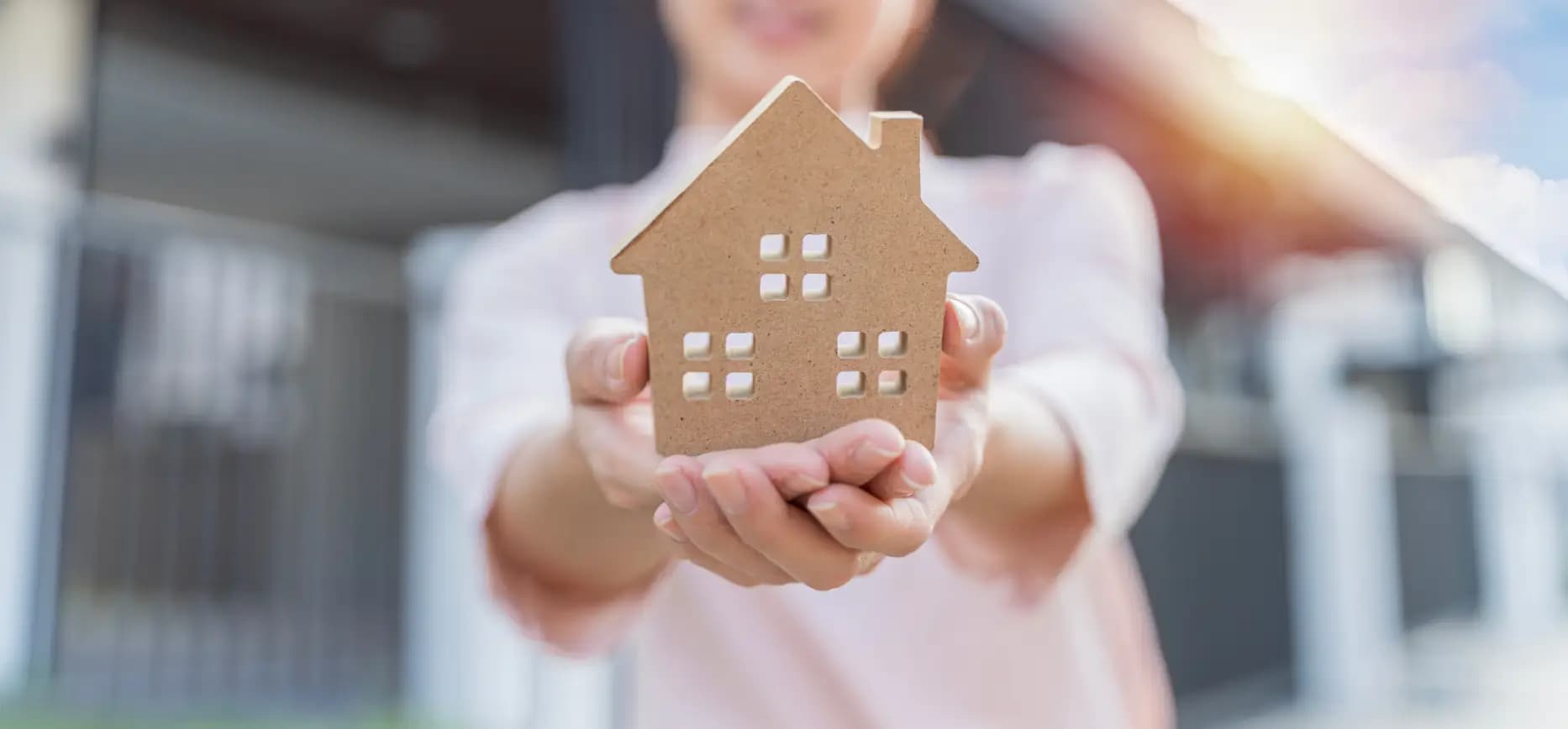 A person holding up a cardboard cut-out of a house.