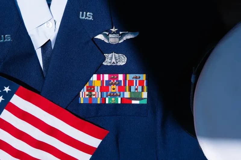 U.S. military dress uniform with service ribbons and a small American flag