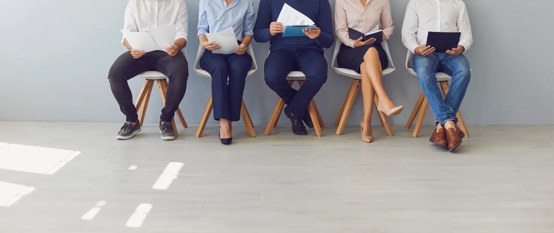 A line of interviewees sitting with their resumes.