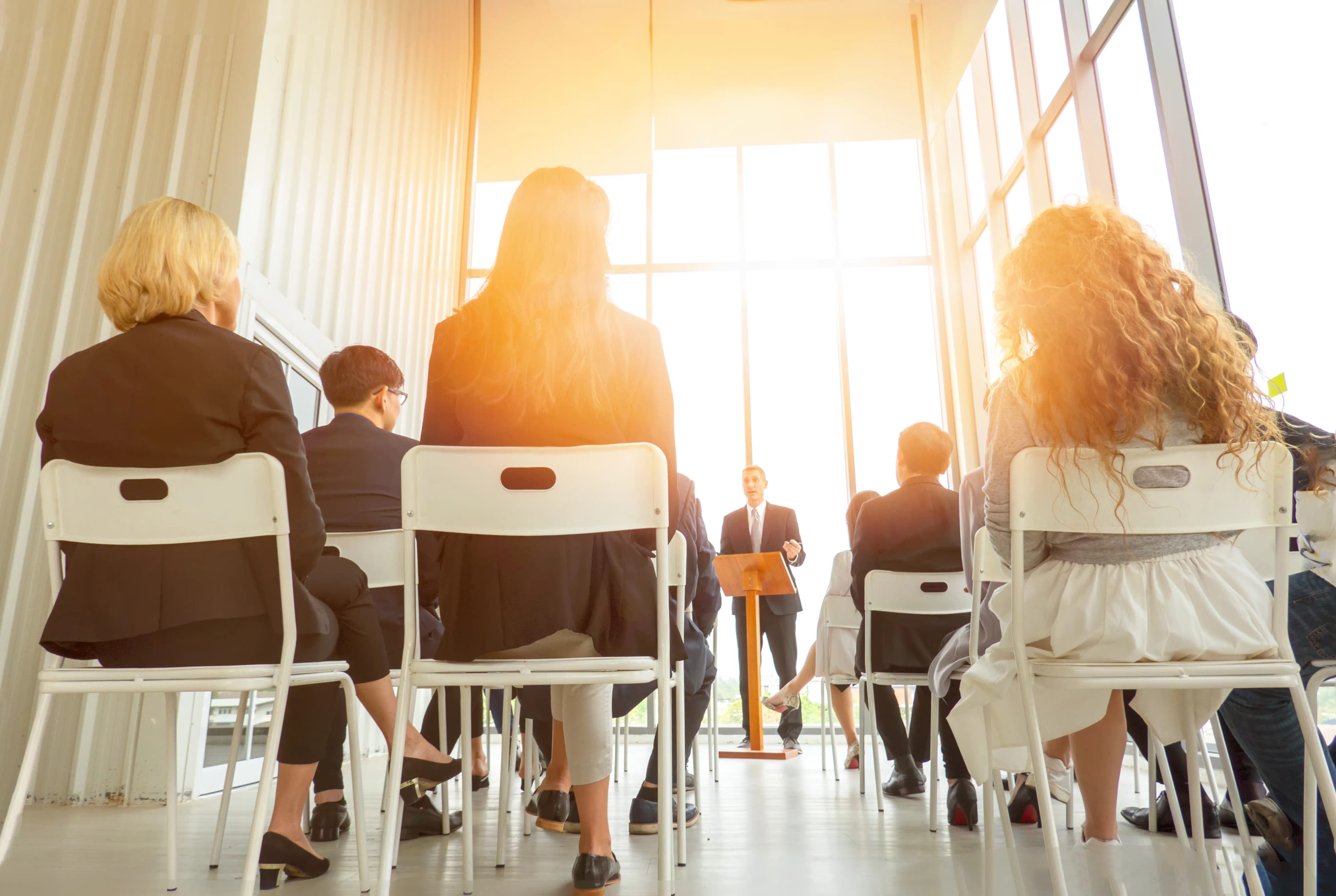 Employees attending a meeting/presentation and listening to a speaker.
